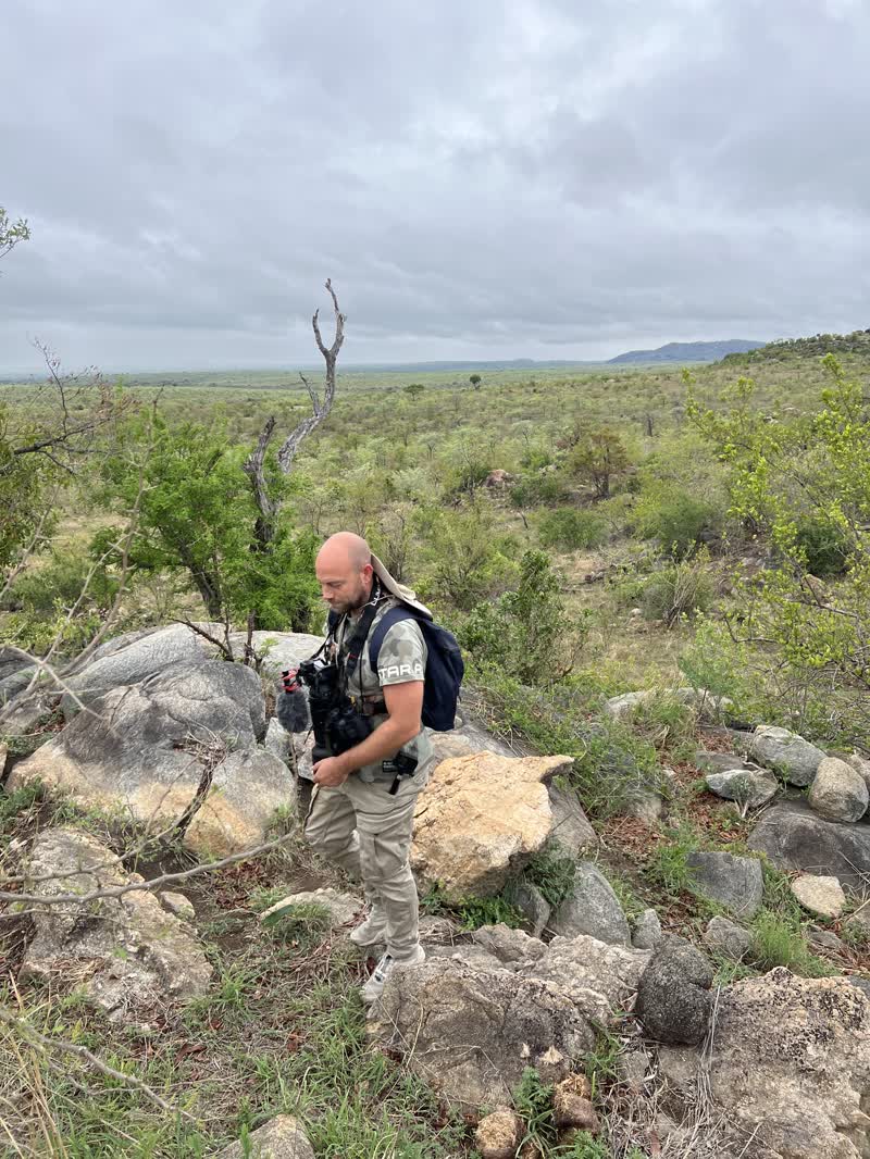 Niek te voet met camera en rugzak op een rotsheuvel in de bush