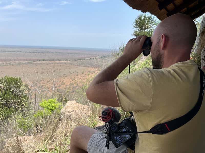 Niek kijkt met de verrekijker uit over een eindeloze Kruger-vlakte