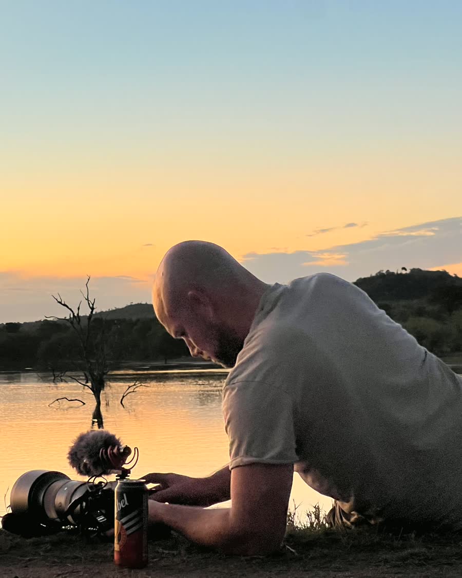 Niek aan de waterkant bij zonsondergang, sleutelend aan zijn camera